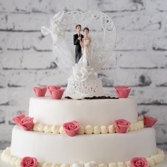 Hochzeitstorte aus Buttercreme zweistöckig mit Brautpaar, Namenszug und einzelnen Rosen